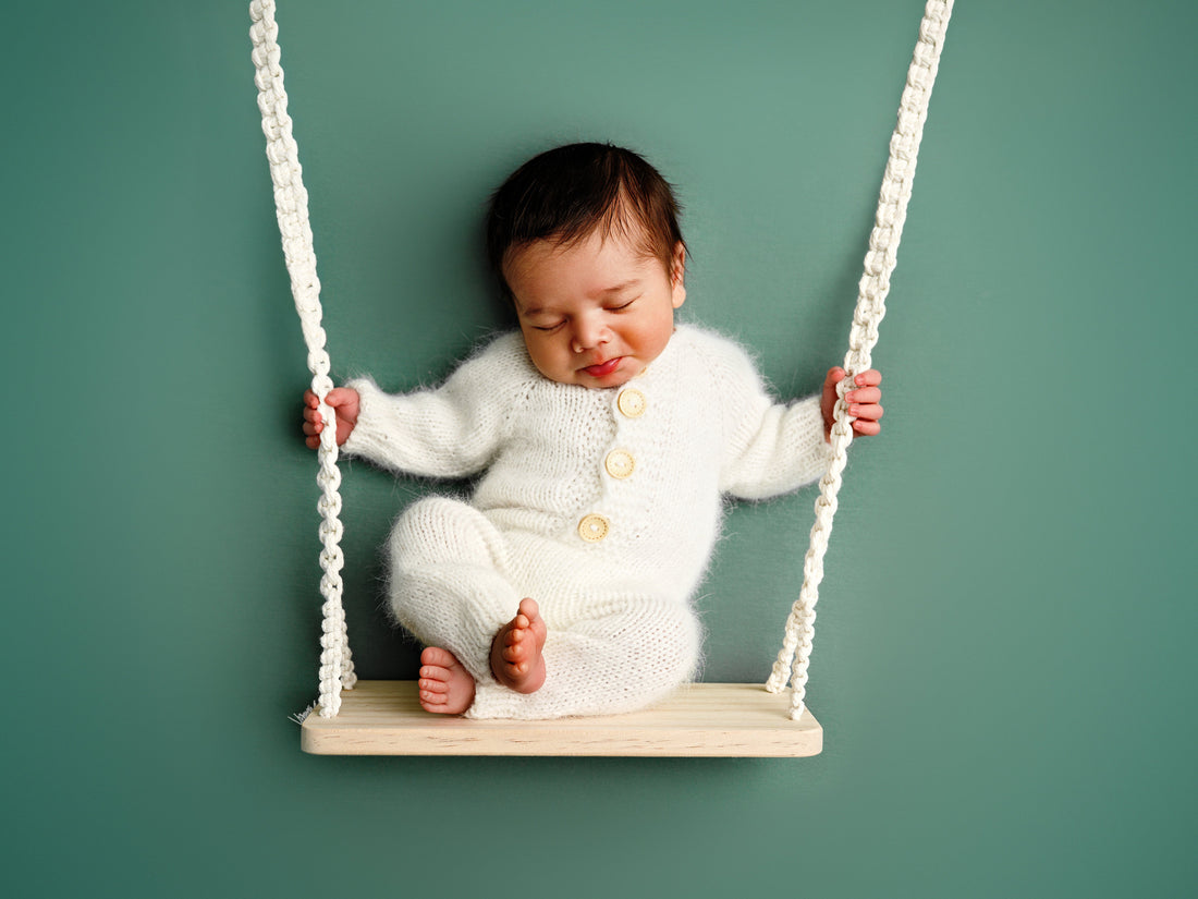 Newborn baby op een schommel tijdens een newborn fotoshoot in de studio